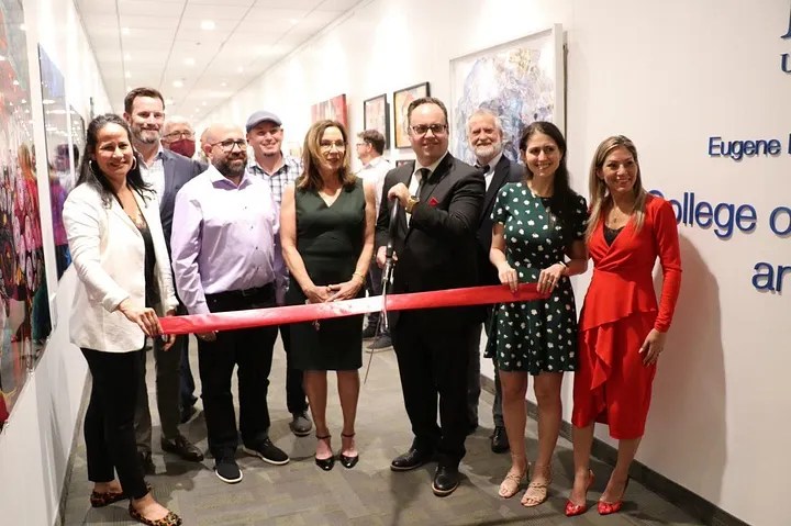 Photo from the opening of the Lynn University NFT Art Museum. Faculty and administrators stand with representatives of the Boca Raton Innovation Campus, where the museum is housed. They are cutting a red ribbon.